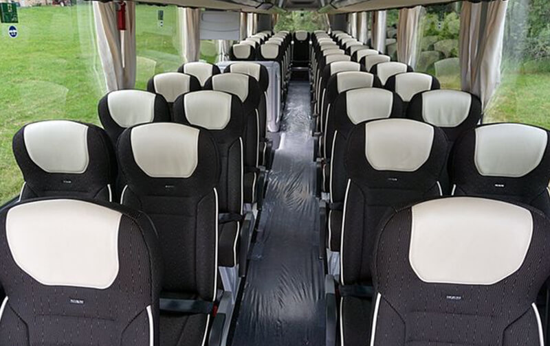 Innenraum eines Reisecars mit verstellbaren Sitzen und Mittelgang